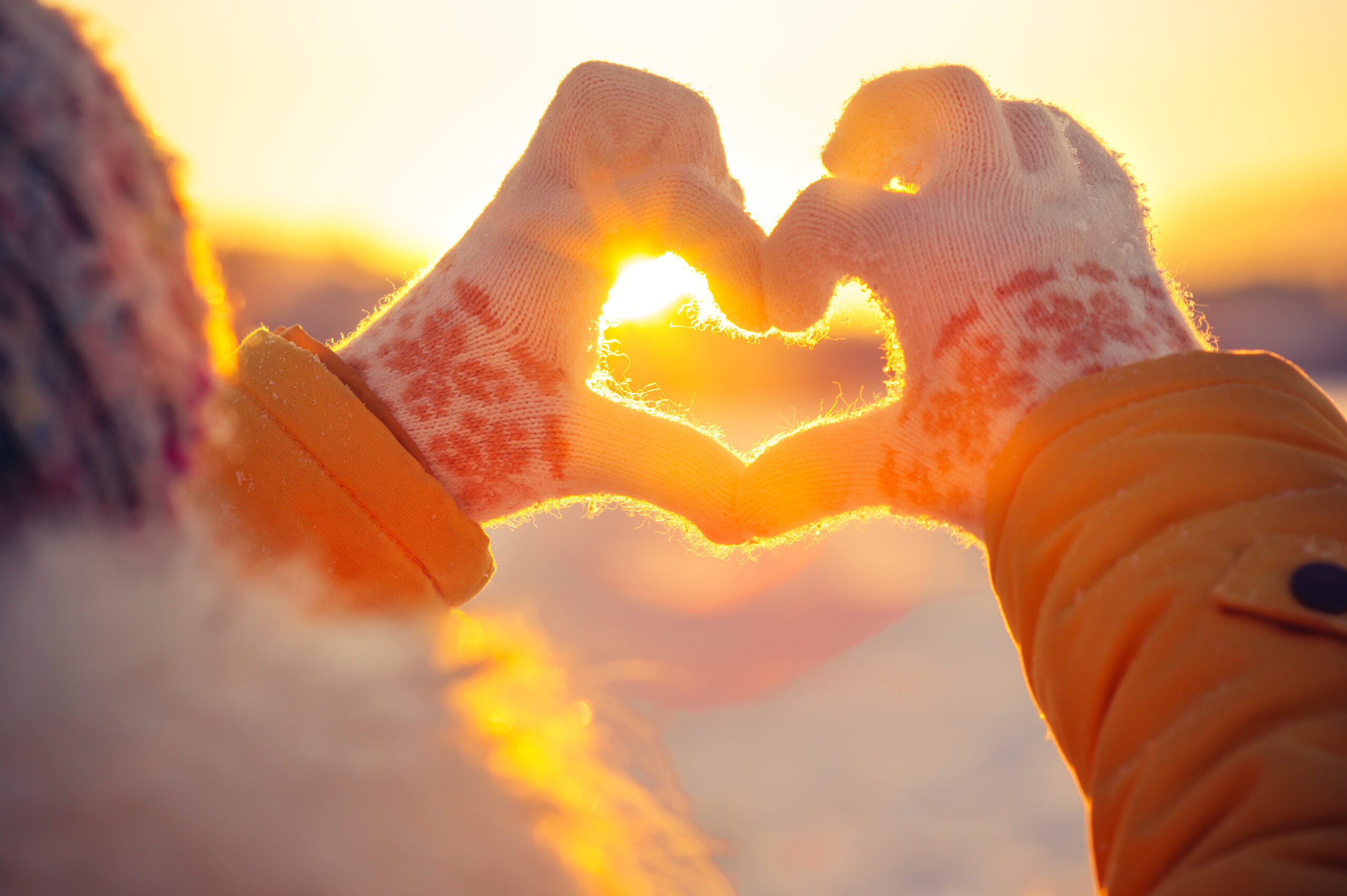 hands making a heart shape in the sunset