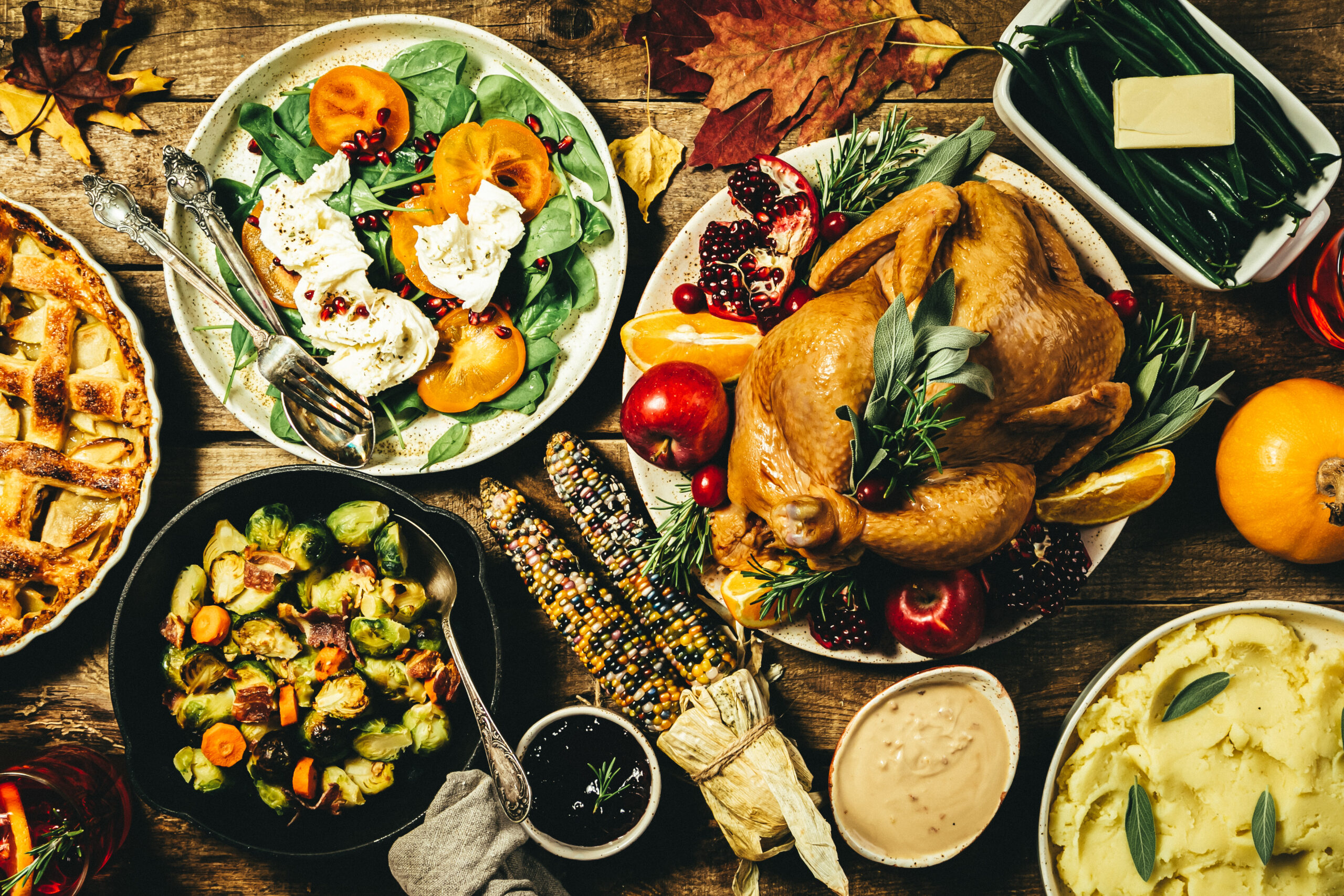 table set with holiday foods including turkey, salad, and other side dishes.
