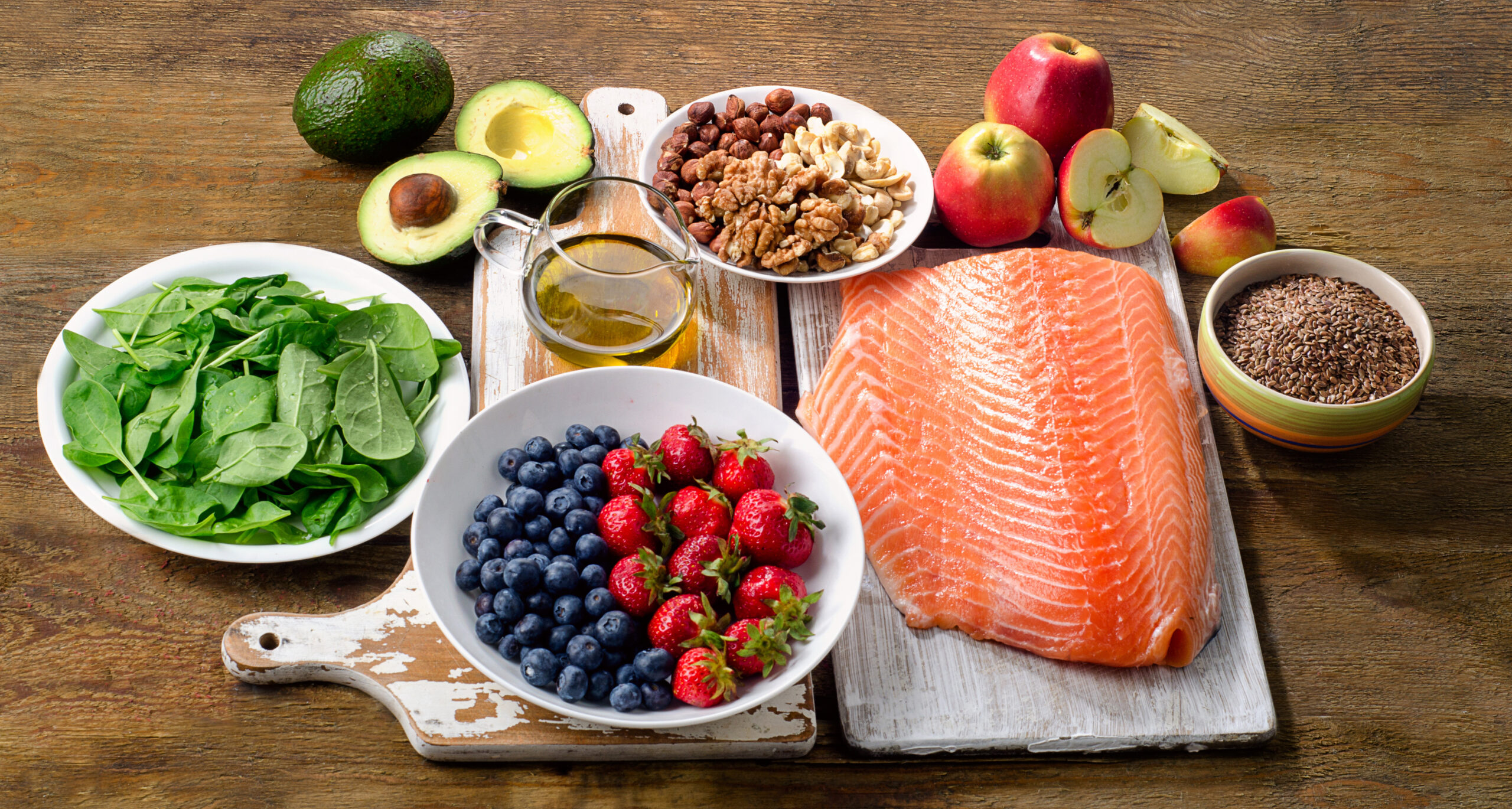 selection of foods on a table, including salmon, berries, greens, and fruits.