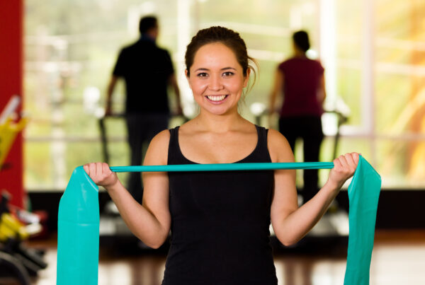 lady smiling while holding a resistance band in front of her body