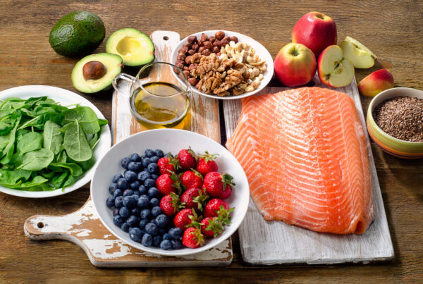 selection of foods on a table, including salmon, berries, greens, and fruits.